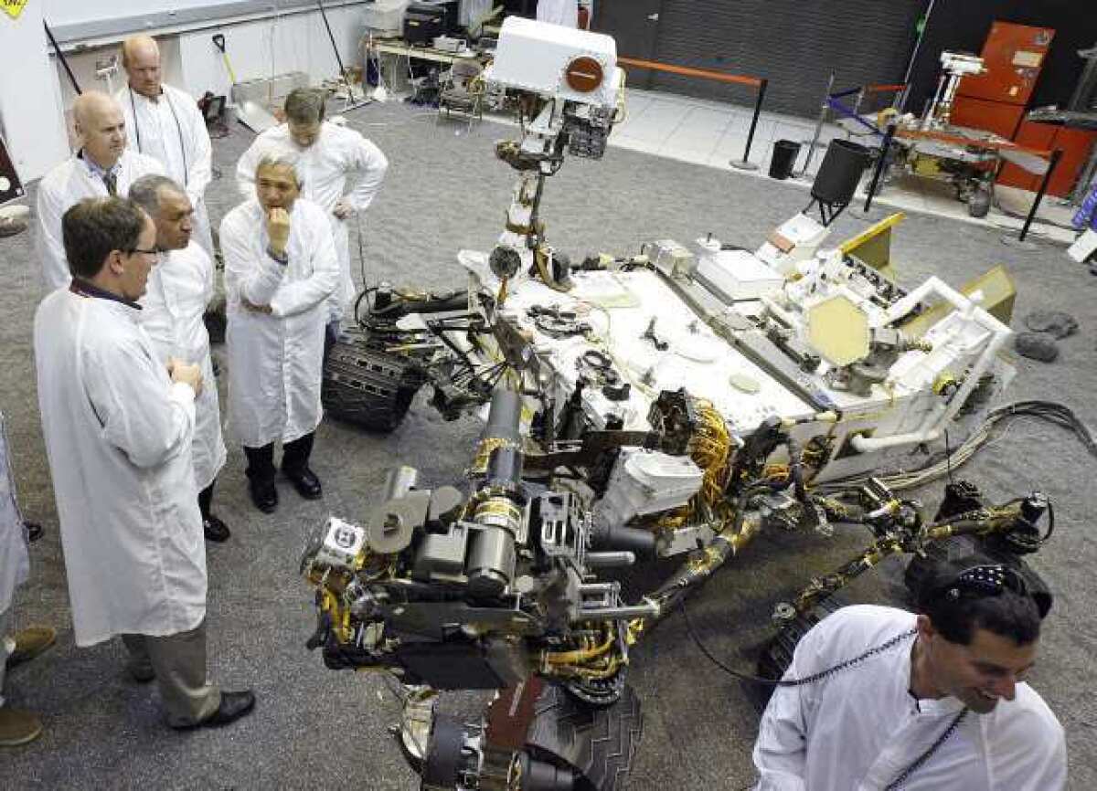 Scientist and engineers stand next to a duplicate of the Mars Rover Curiosity at JPL.