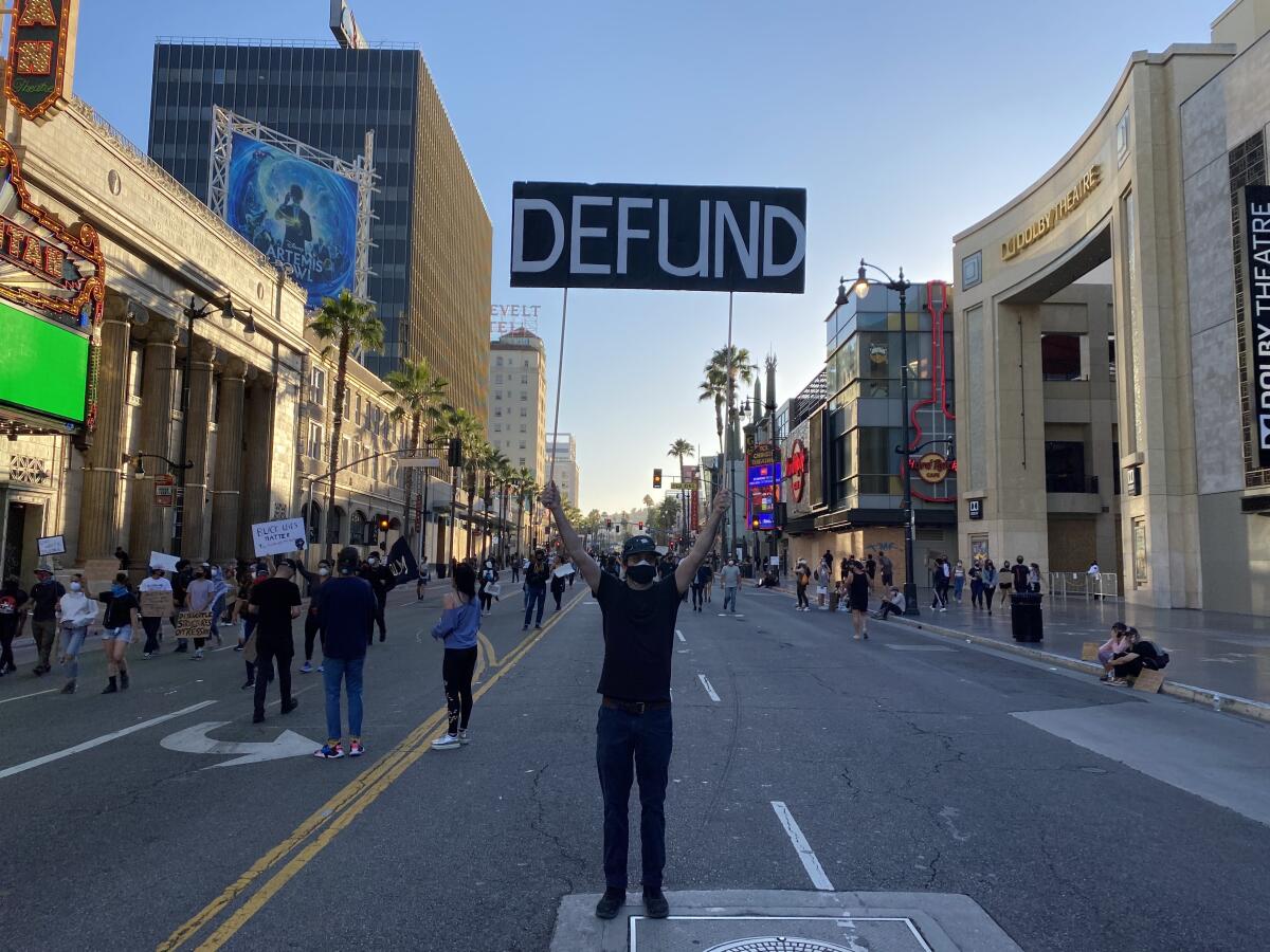 A protester holds up a sign calling for the LAPD to be defunded in Hollywood.