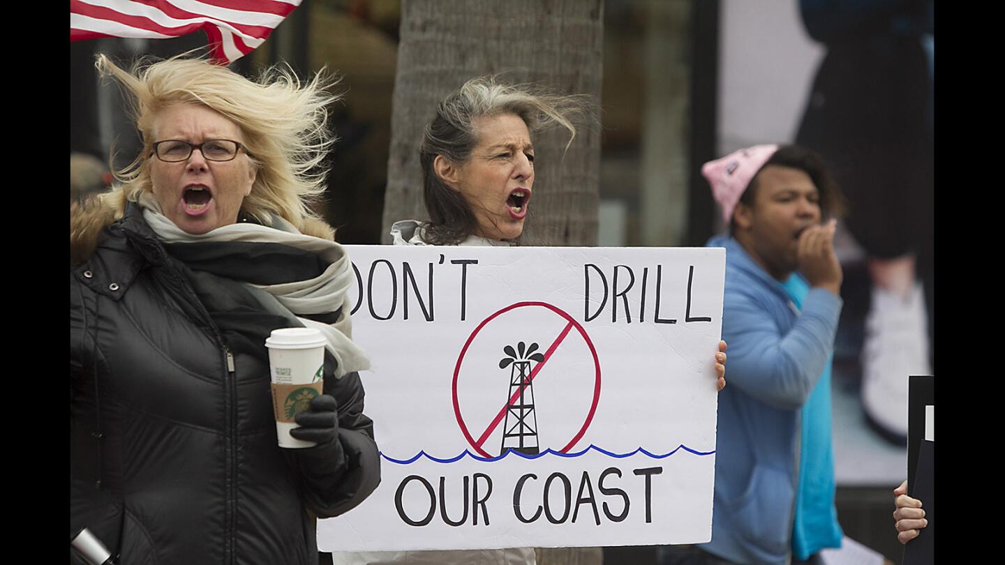 Joni Nichols, holding the sign, joins others in Huntington Beach on Tuesday in protesting President's Trump's plan to open California waters to new offshore drilling.