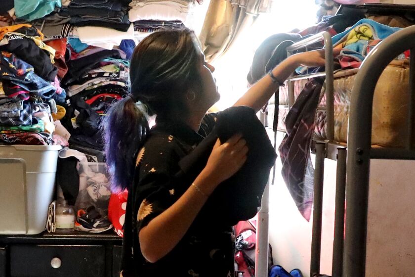 Angie Davila, 20, the oldest of six children, organizes her belongings on top bunk bed in the family's one-bedroom apartment