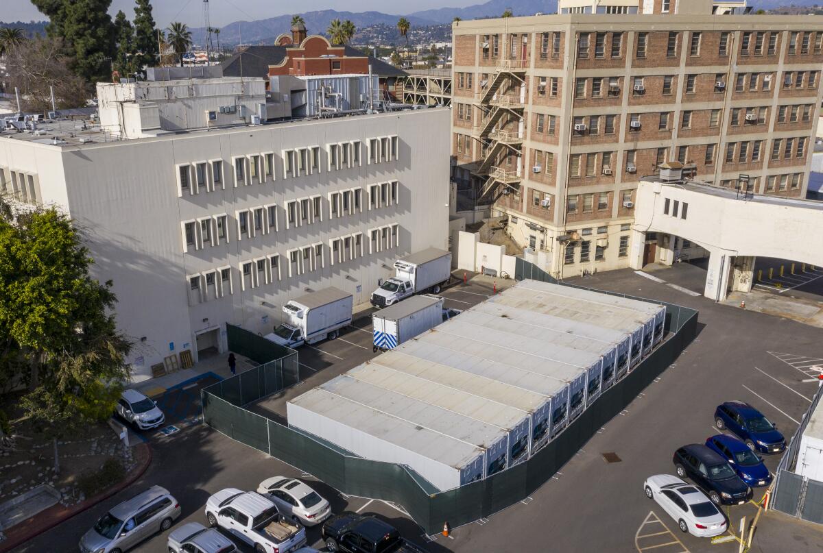 A dozen refrigerated storage containers are lined up in the parking lot at the Los Angeles County coroner's complex.