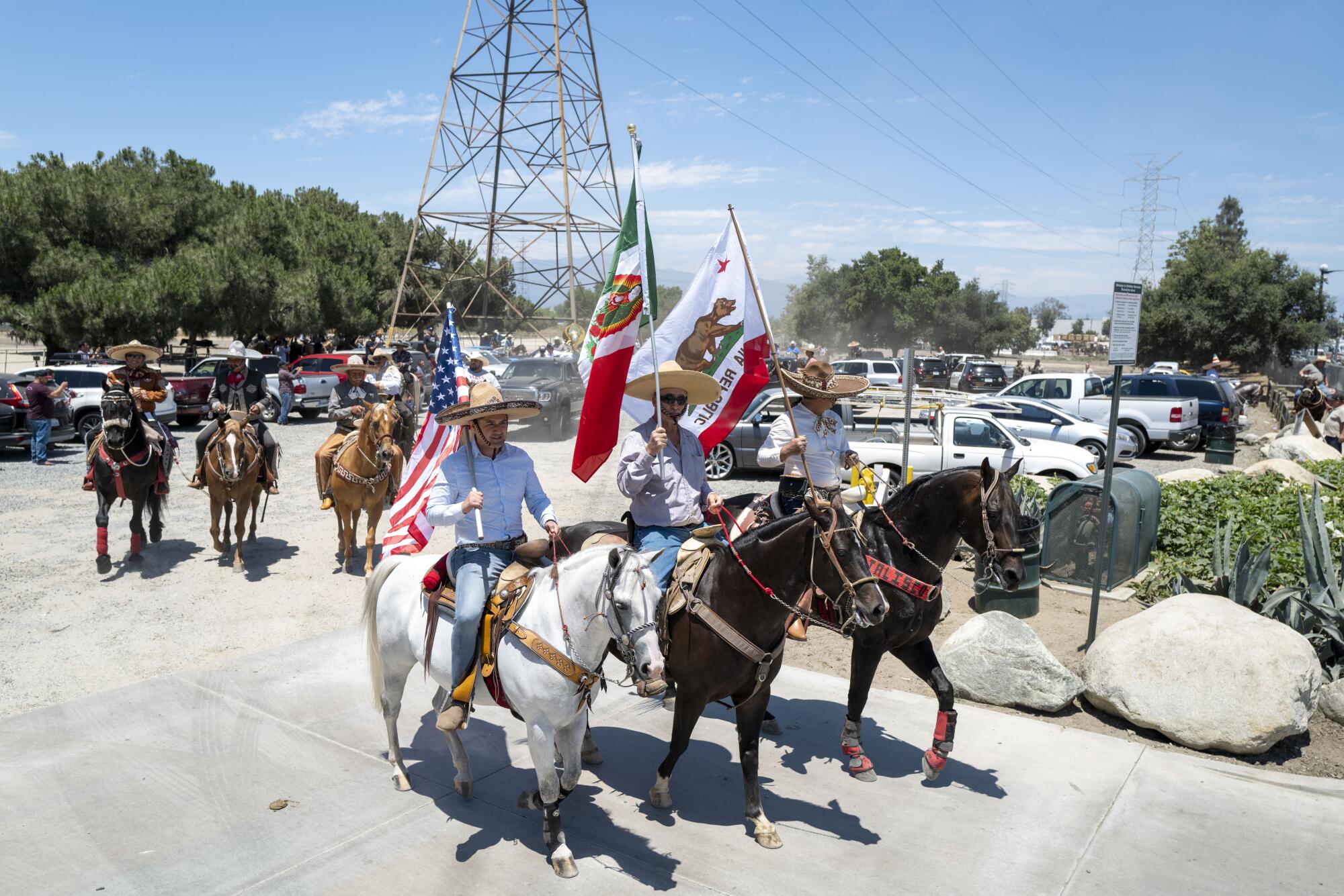 People on horses ride while carrying flags through streets.