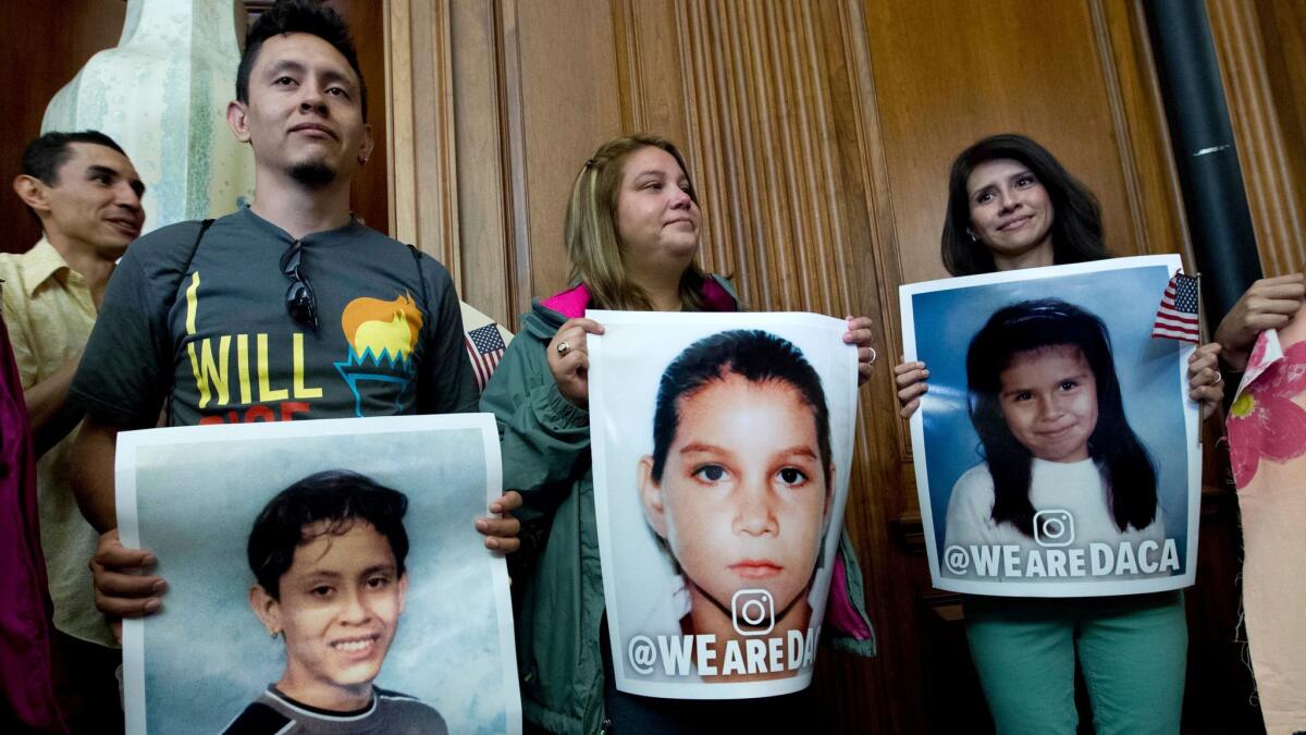 Immigrants who arrived in the U.S. as children hold pictures of their younger selves during a Sept. 6, 2017, news conference by congressional Democrats about President Trump's decision to end the DACA program.