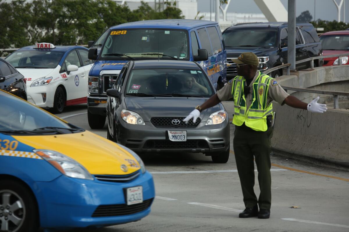 A car with Uber and Lyft stickers on its windshield leaves the departure level at LAX. Soon ride-share operations should be able to pick up and drop off at the airport.