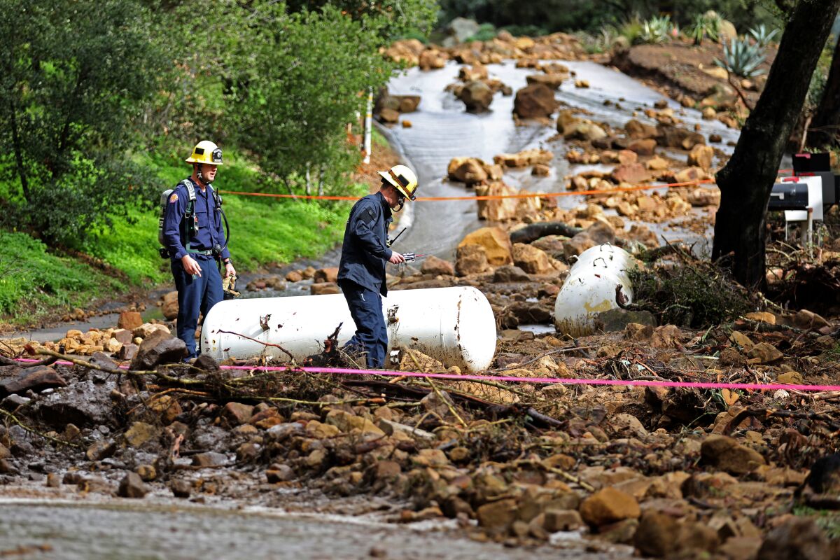 Firefighters stand next to two 500-gallon propane tanks that were washed up