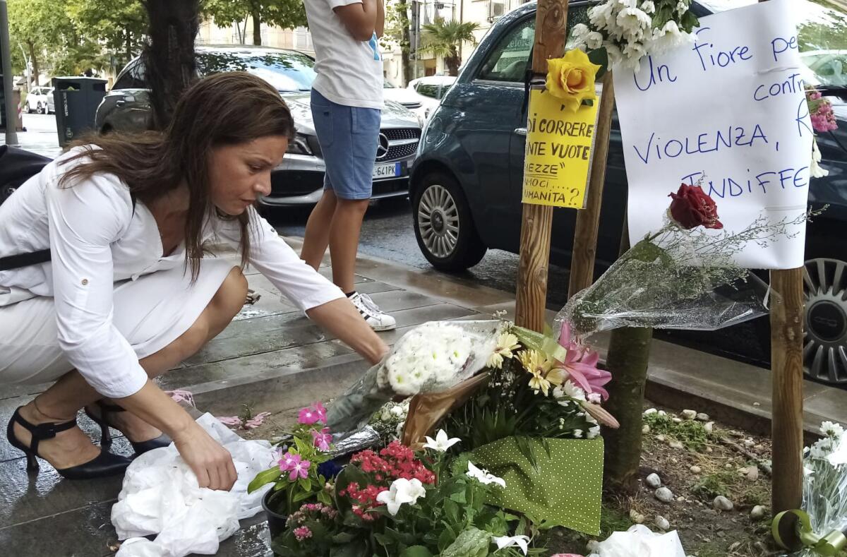 FILE - A woman places a bouquet of flowers where Nigerian street vendor Alika Ogorchukwu was murdered, in Civitanova Marche, Italy, Saturday, July 30, 2022. A judge in Italy on Monday ordered an Italian man to remain jailed as an investigation continues into the brutal beating of Ogorchukwu, a slaying that shocked many in Italy and provoked the condemnation of the Nigerian government. (AP Photo/Chiara Gabrielli, File)