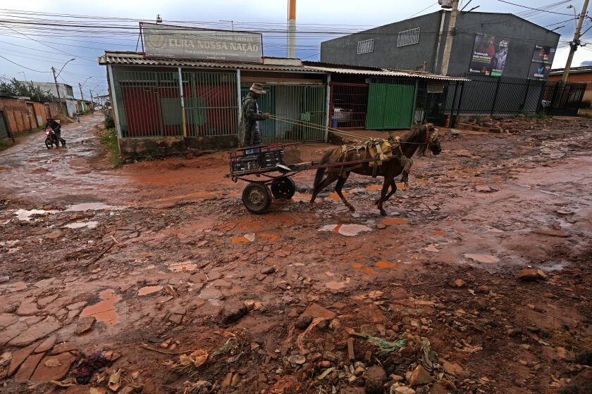 A resident drives his wagon down a street of the Sol Nascente favela of Brasilia, Brazil, Monday, March 20, 2023. Sol Nascente, which means Rising Sun, is now Brazil's most populous, and has unpaved, impassable roads, which flood frequently during the months of summer rains. (AP Photo/Eraldo Peres)