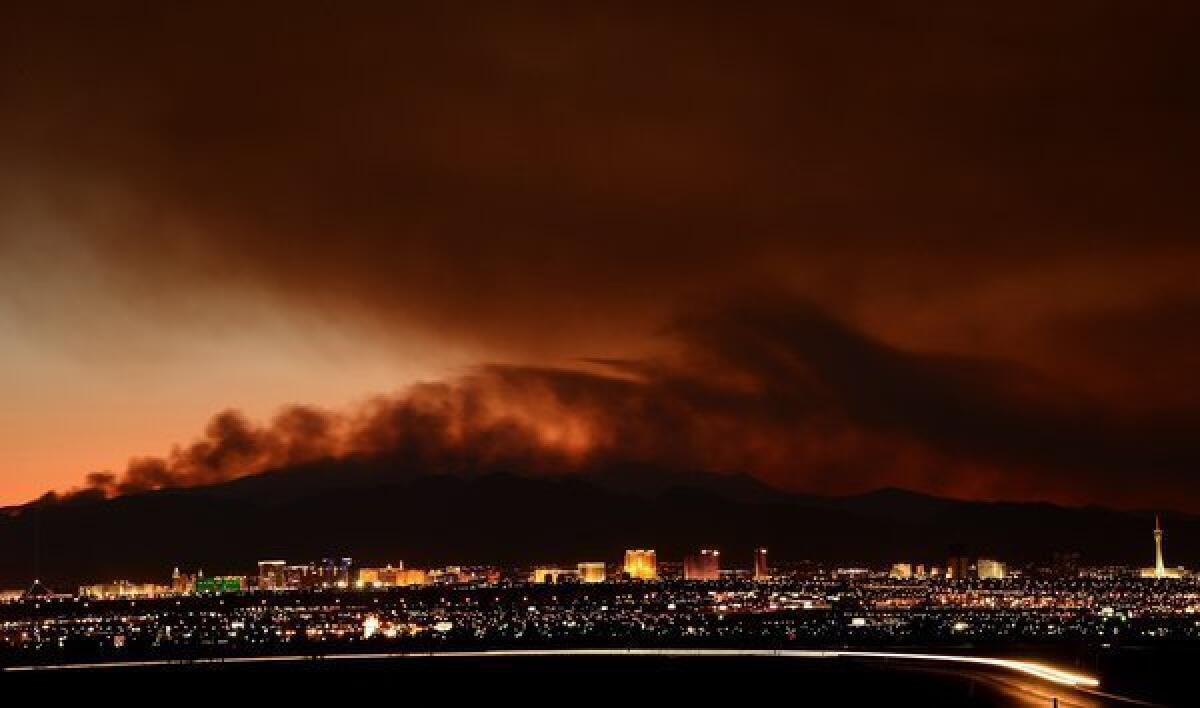 Smoke from the Carpenter 1 fire in the Spring Mountains range is illuminated by the setting sun as it billows behind hotel-casinos on the Las Vegas Strip. Nearly 20,000 acres have burned since lightning sparked the blaze July 1 in Carpenter Canyon on the Pahrump, Nev., side of Mount Charleston. More than 800 firefighters are battling the wildfire.