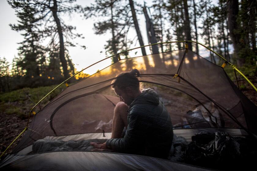 LITTLE GRASS VALLEY, CA -JUNE 23, 2021: As dusk settles in, Sammy Potter of Maine rubs his feet inside his one-man tent after a day of hiking 25 plus miles with hiking partner Jackson Parell along the Pacific Crest Trail in the Plumas National Forest on June 23, 2021 in Little Grass Valley, California. The Stanford students are attempting to complete the Triple Crown of hiking in one calendar year. This includes hiking all three major trails: the PCT(Pacific Crest Trail), the CDT (Continental Divide Trail) and the AT (Appalachian Trail). (Gina Ferazzi / Los Angeles Times)