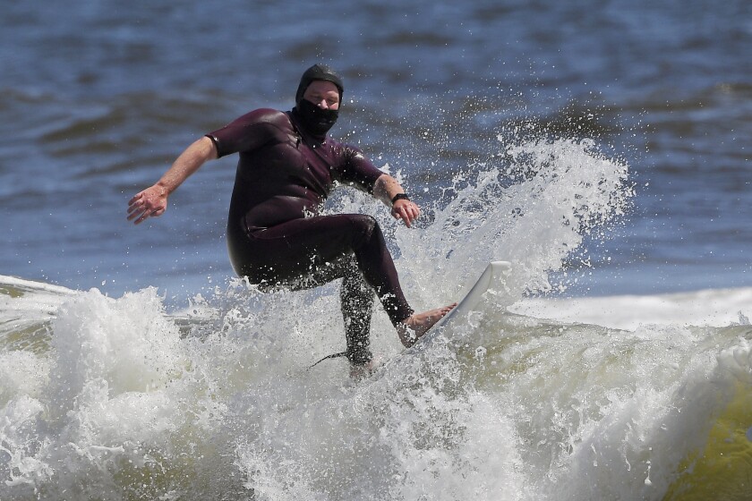 Tim O'Rourke surfs with a face covering to protect him from the coronavirus at Venice Beach as Los Angeles County reopened its beaches, which had been closed for nearly two months.