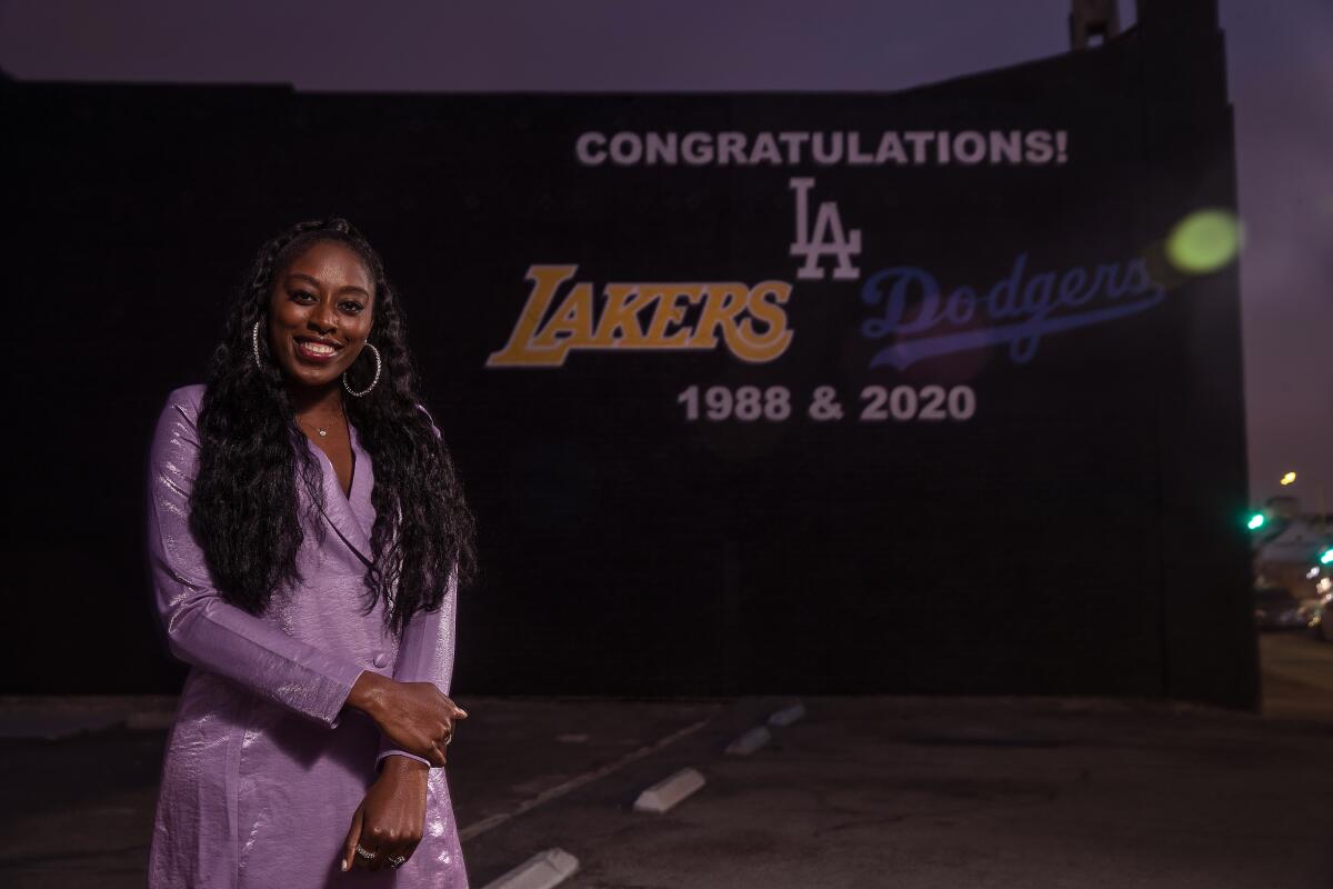 Sparks star Chiney Ogwumike poses for a photo in front of a mural on 3rd Street honoring the Lakers and Dodgers titles.