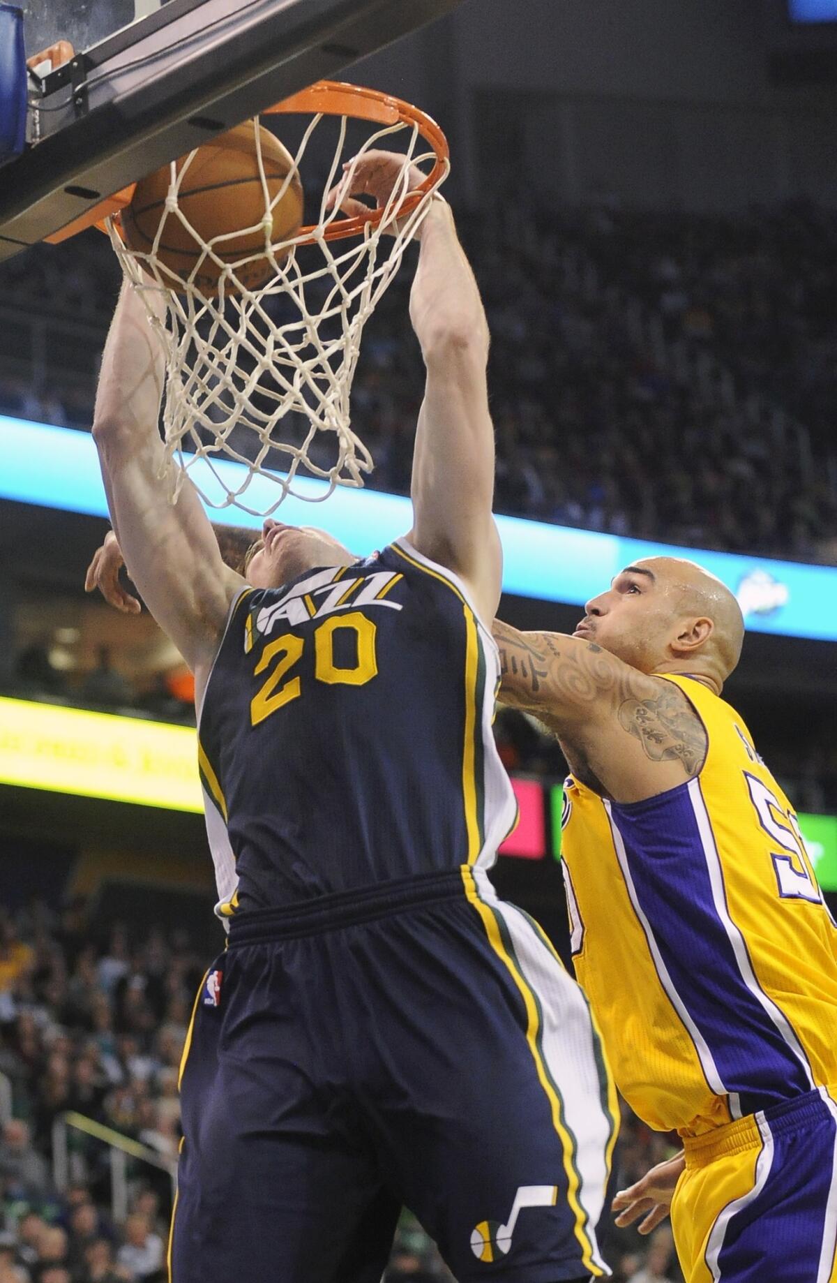 Utah Jazz guard Gordon Hayward, left, dunks in front of Lakers center Robert Sacre during the second half of the Lakers' 105-103 loss Friday.