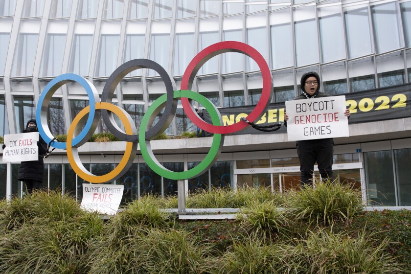 Protesters hold protest posters during a protest against Beijing 2022 Winter Olympics by activists of the Tibetan Youth Association in Europe front of the International Olympic Committee (IOC) headquarters in Lausanne, Switzerland, Saturday, Dec. 11, 2021. (Jean-Guy Python/Keystone via AP)