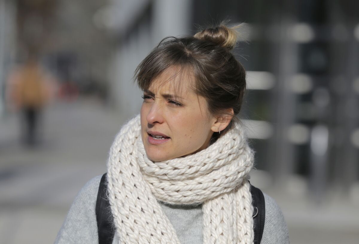 A picture of a woman outdoors wearing a white knit scarf