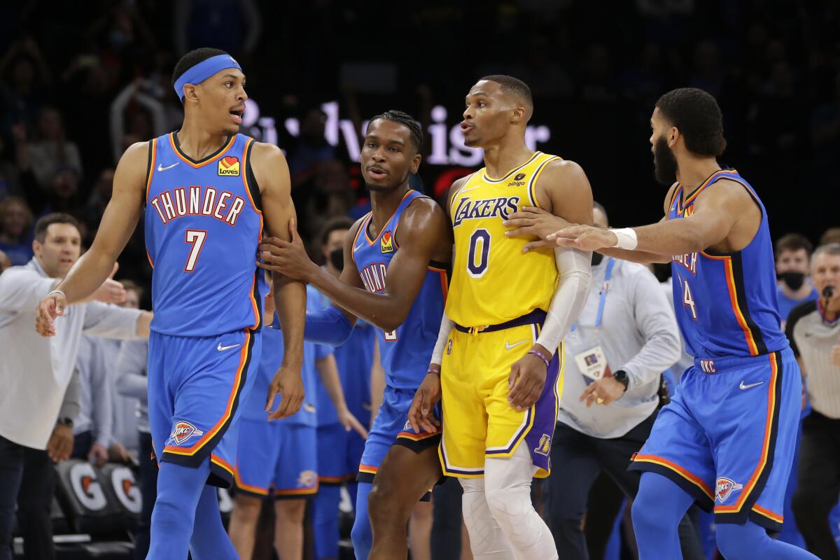 Two Thunder players grab the arms of teammate and Lakers' Russell Westbrook as they have words on court