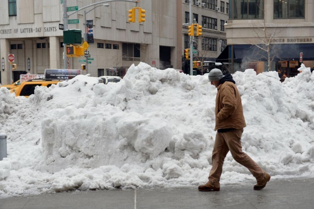 A man walks past a pile of snow in Manhattan after the latest storm dropped more snow on the Northeast and caused a buildup of ice. Some areas reported salt shortages because of the unusually snowy winter.