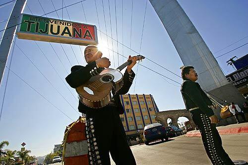 It's another slow day at Plaza Santa Cecilia, the gateway to Tijuana's tourist district. Juan Manuel Monsivais, left, and Telesforo Magana wait for passers-by to hire their mariachi band. Tourism in the city is down 90% since 2005.