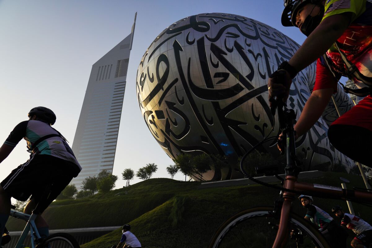 Bicyclists ride past the Museum of the Future and Emirates Towers in Dubai, United Arab Emirates, Friday, Nov. 5, 2021. The annual Dubai Ride saw authorities shut down the skyscraper-lined super highway that cuts through the center of the city-state to allow bicyclists to ride on it. Organizers say 32,750 people took part in the ride Friday. (AP Photo/Jon Gambrell)
