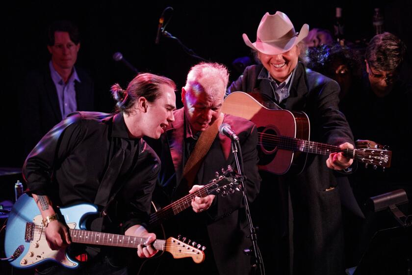 Veteran singer-songwriter John Prine, center, is flanked by his son, Jody, left, and roots country star Dwight Yoakam and soul singer Bettye LaVette during the finale of an all-star Americana tribute to his music Saturday at the Troubadour in West Hollywood.