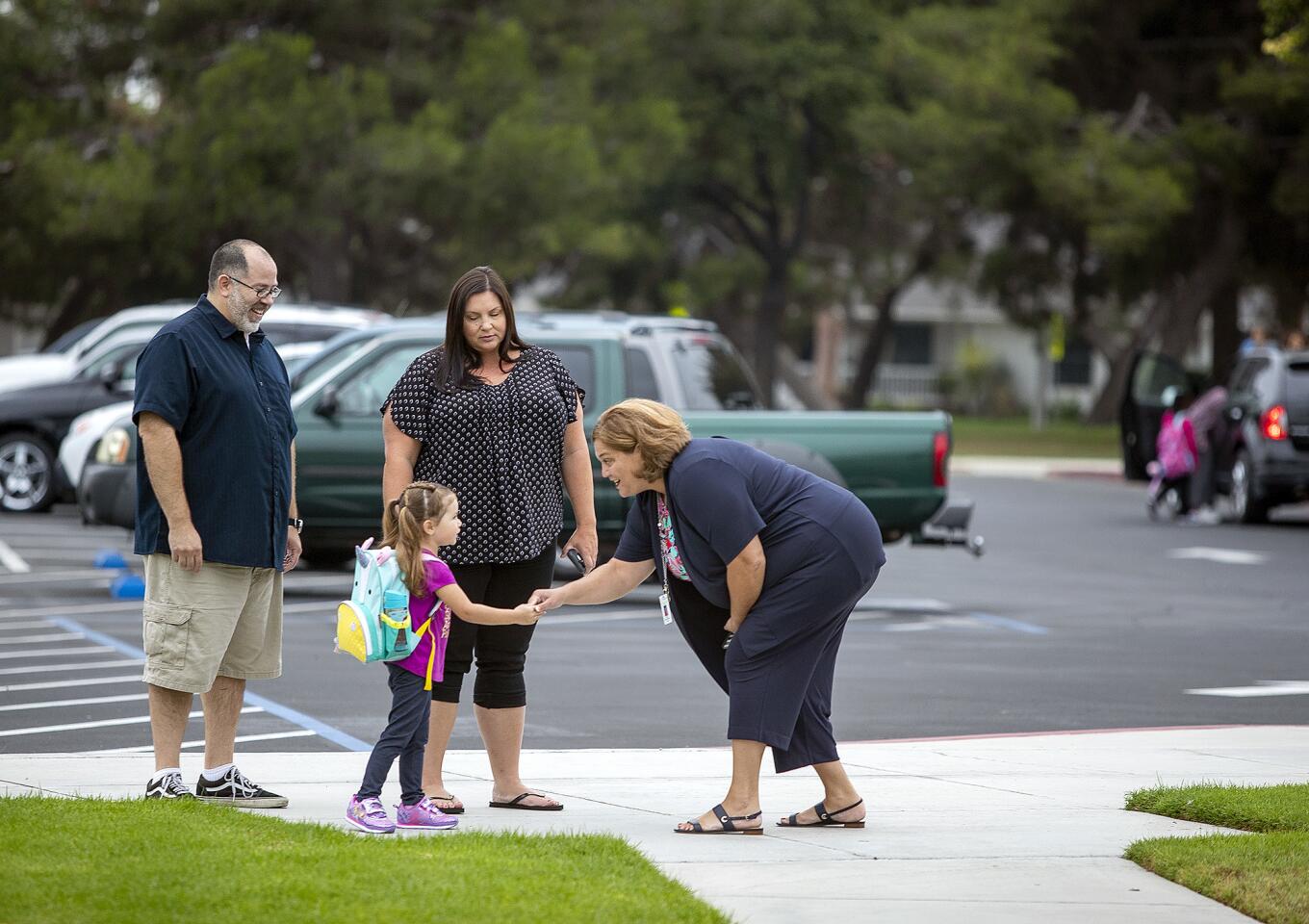 Stacey DeBoom-Howard, the new principal at Adams Elementary School in Costa Mesa, introduces herself to Sierra Herndon, 4, as parents Jorge Suarez and Melanie Smith watch on Tuesday, the first day of school for the Newport-Mesa Unified School District.