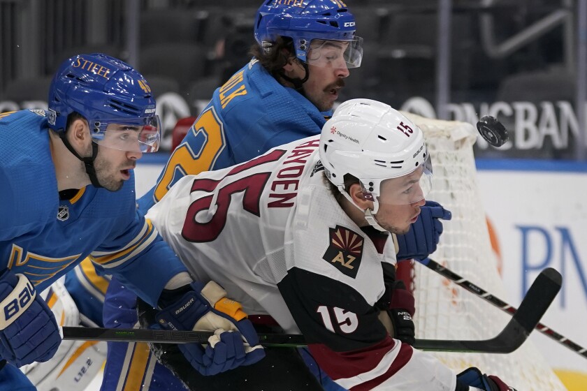 St. Louis Blues' Jake Walman, left, chases after a loose puck along with teammate Justin Faulk (72) and Arizona Coyotes' John Hayden, right, during the third period of an NHL hockey game Saturday, Feb. 6, 2021, in St. Louis. (AP Photo/Jeff Roberson)