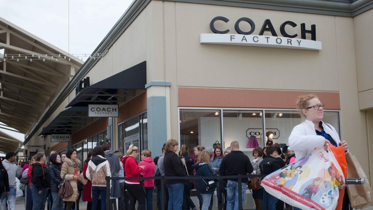 Shoppers wait in line outside a Coach factory outlet store in Monroe, Ohio, in 2015.