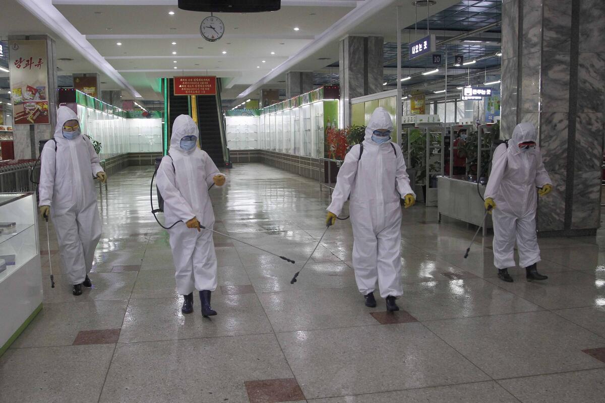 Suited cleaners disinfecting a store in Pyongyang, North Korea
