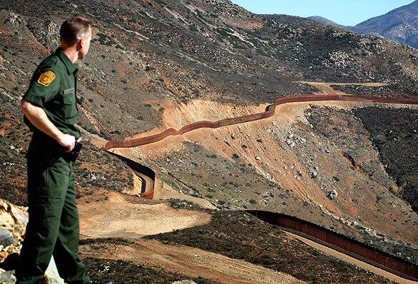 Border Patrol spokesman Jerome C. Conlin gazes across the base of Otay Mountain at a recently completed stretch of the U.S.-Mexico border fence. The 3.6-mile barrier through rugged terrain east of San Ysidro cost about $57 million to construct.
