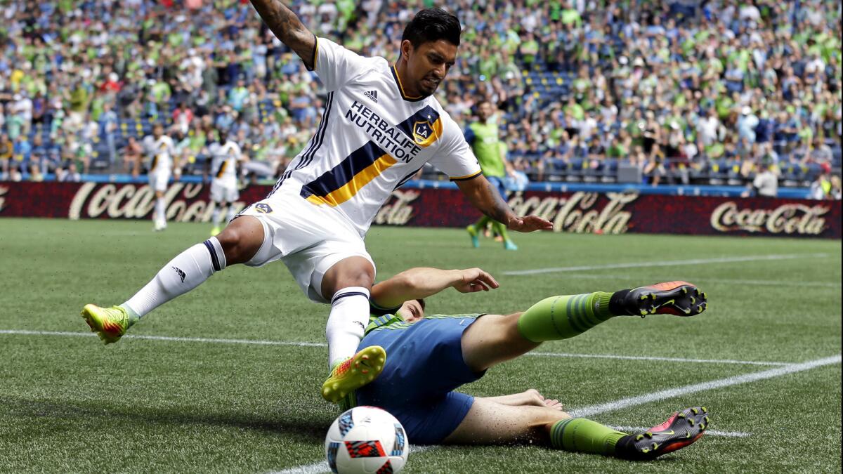 Galaxy defender A. J. DeLaGarza is taken out by the tackle of Sounders midfielder Jordan Morris in the first half Sunday.