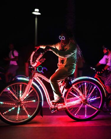 Cyclists riding bikes decorated with colored lights at night