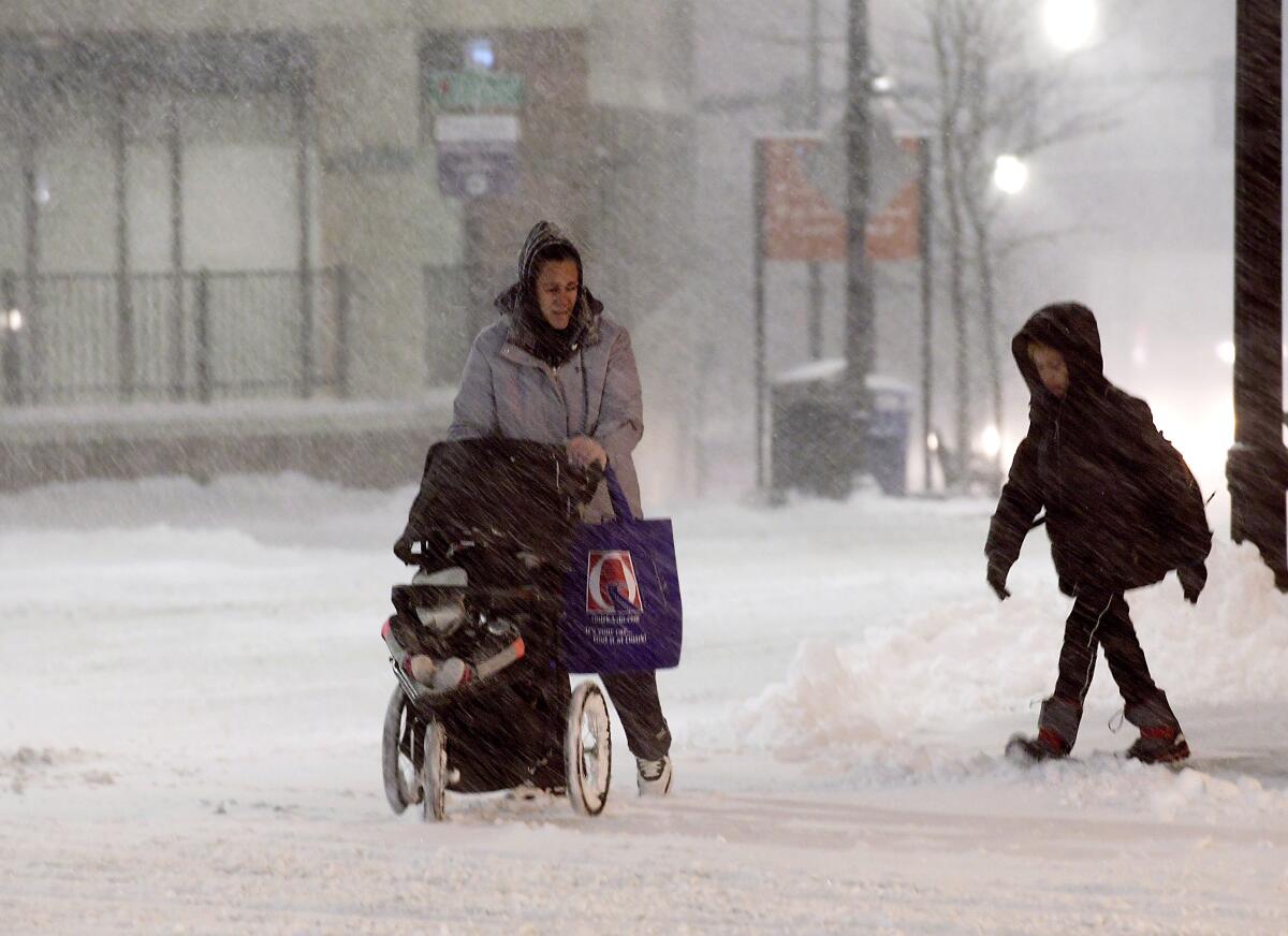 A family walks up Front Street during a snow storm in Worcester, Mass., on Sunday.