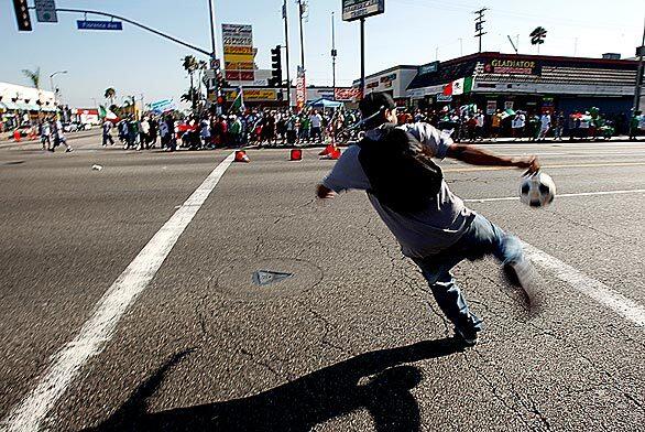 A fan kicks a soccer ball across Slauson Avenue in Huntington Park after the Mexican national soccer team's victory over the U.S. in a World Cup qualifying match in Mexico City. The celebrations were raucous but largely peaceful in the heavily Latino community southeast of downtown Los Angeles.