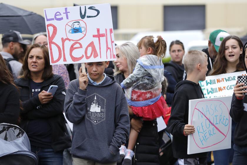 Kids and parents including Chase Beamish, 12, with sign, participate in the "Let the Kids Breathe" rally in front of Orange County Department of Education building in Costa Mesa on Monday. The effort is to call on Orange County educators to remove mask mandates for public schools including Orange County.