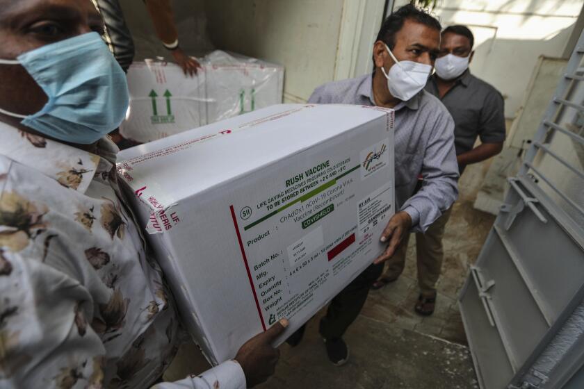 Health workers shift a box containing COVID-19 vaccine from a vehicle to a cold storage at Civil Hospital in Ahmedabad, India, Tuesday, Jan. 12, 2021. On Jan. 16 India will start the massive undertaking of inoculating an estimated 30 million doctors, nurses and other front line workers, before attention turns to around 270 million people who are either aged over 50 or have co-morbidities. (AP Photo/Ajit Solanki)