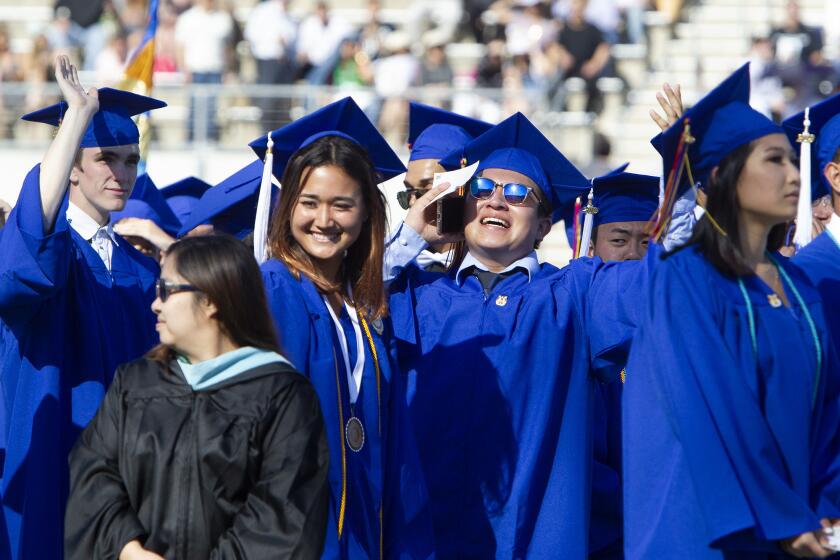 A graduate uses his phone to find family and friends in the stands during Fountain Valley High School's graduation ceremony Wednesday at LeBard Stadium at Orange Coast College in Costa Mesa.