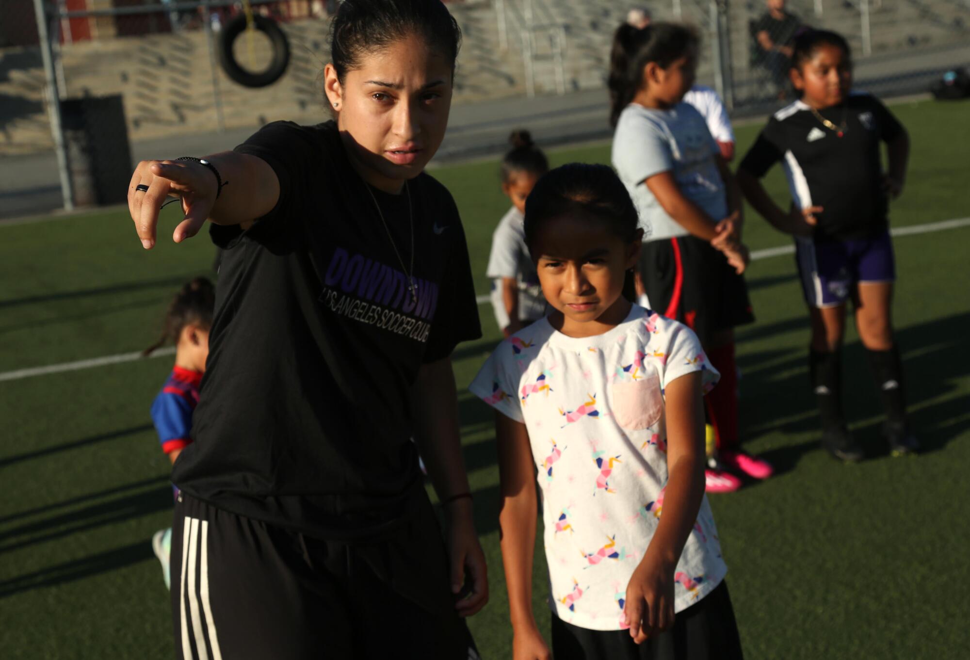 Nayelli Barahona points and gives directions to a young girl during a Downtown L.A. Soccer Club practice.