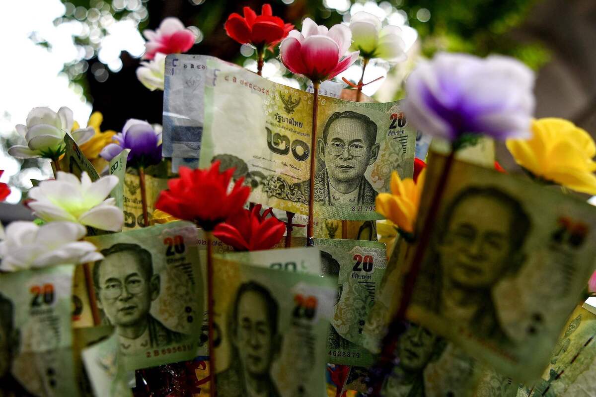 Thai baht banknotes bearing a picture of late King Bhumibol Adulyadej are seen on a street in Bangkok on Tuesday.
