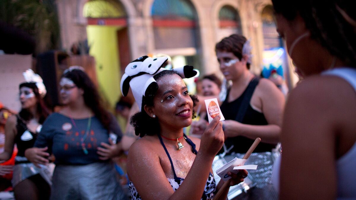 A woman distributes anti-sexual-harassment stickers during a carnival block party in Rio de Janeiro, Brazil.