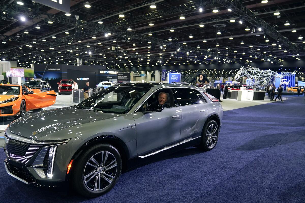 PresidentBiden drives a Cadillac Lyriq through the show room at the Detroit Auto Show.