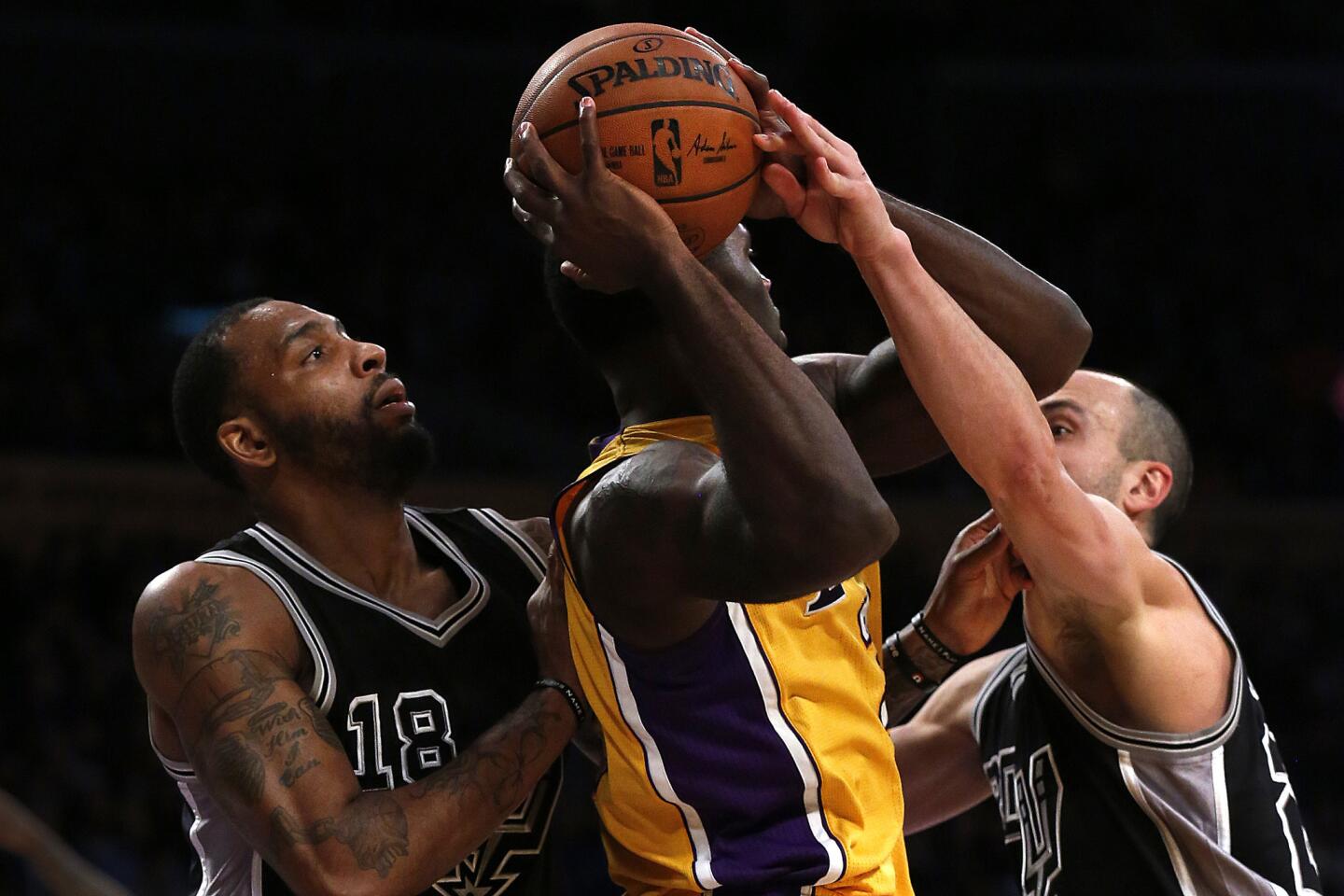 Lakers forward Brandon Bass looks to pass out of the double-team defense of Spurs forward Rasual Butler, left, and guard Manu Ginobili.