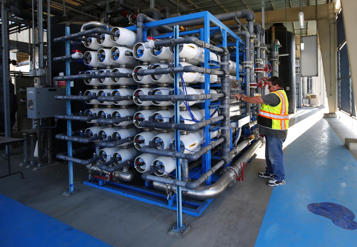 A worker in a safety vest in a room full of reverse osmosis filters for Pure Water