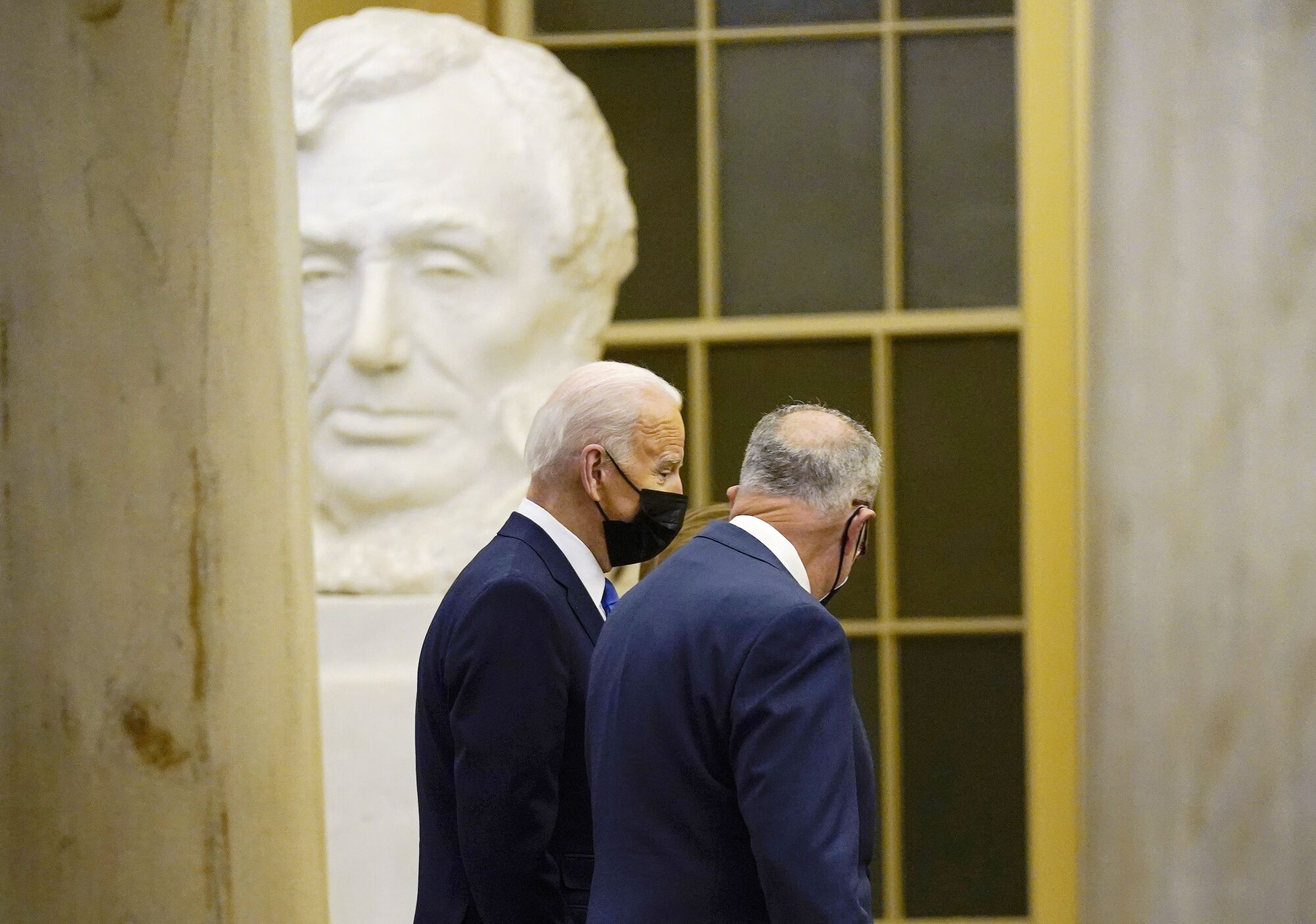President Biden walks with Senate Majority Leader Charles E. Schumer past a statue of Abraham Lincoln at the Capitol
