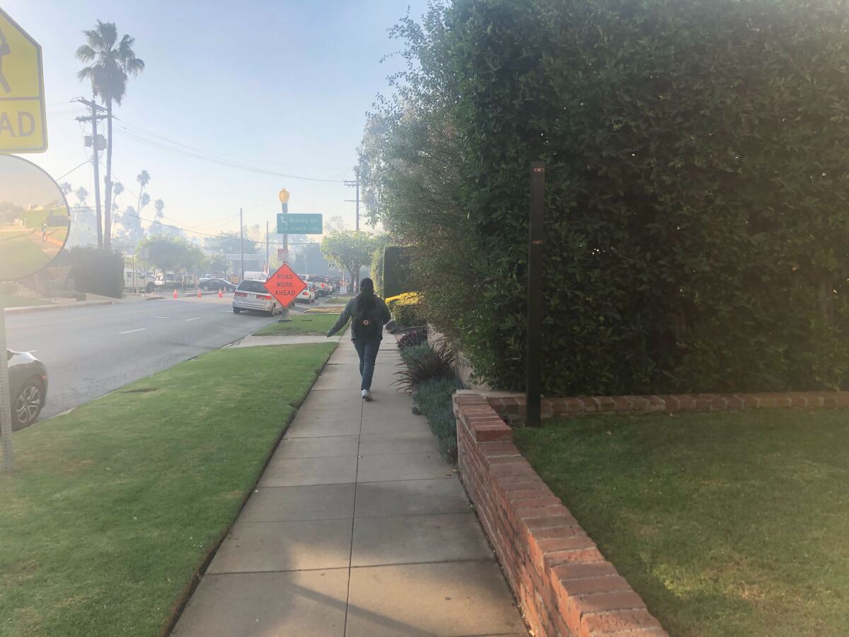 Ana Martinez walks through a neighborhood evacuated in the Getty fire on Monday.