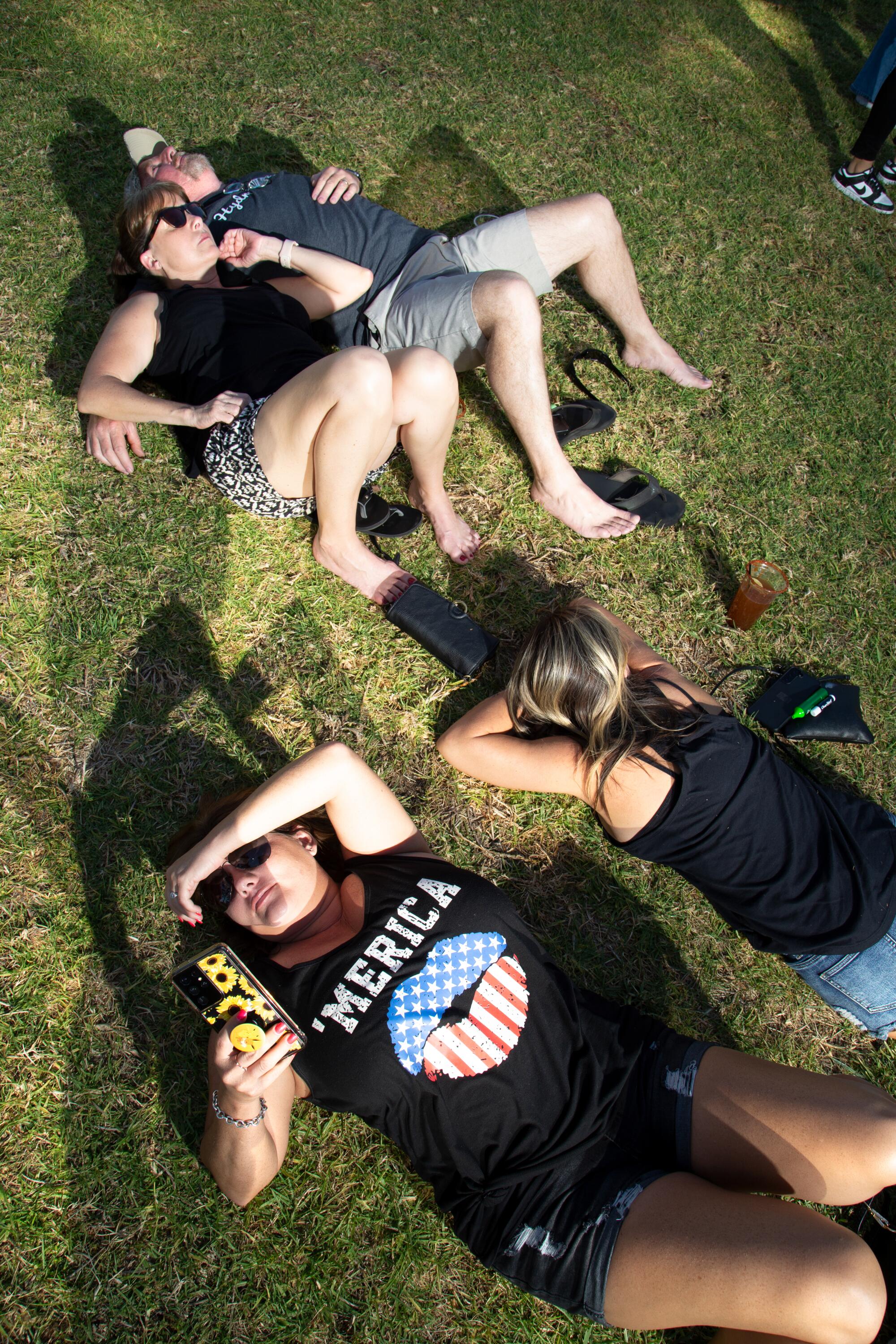 Fairgoers lie in the grass.