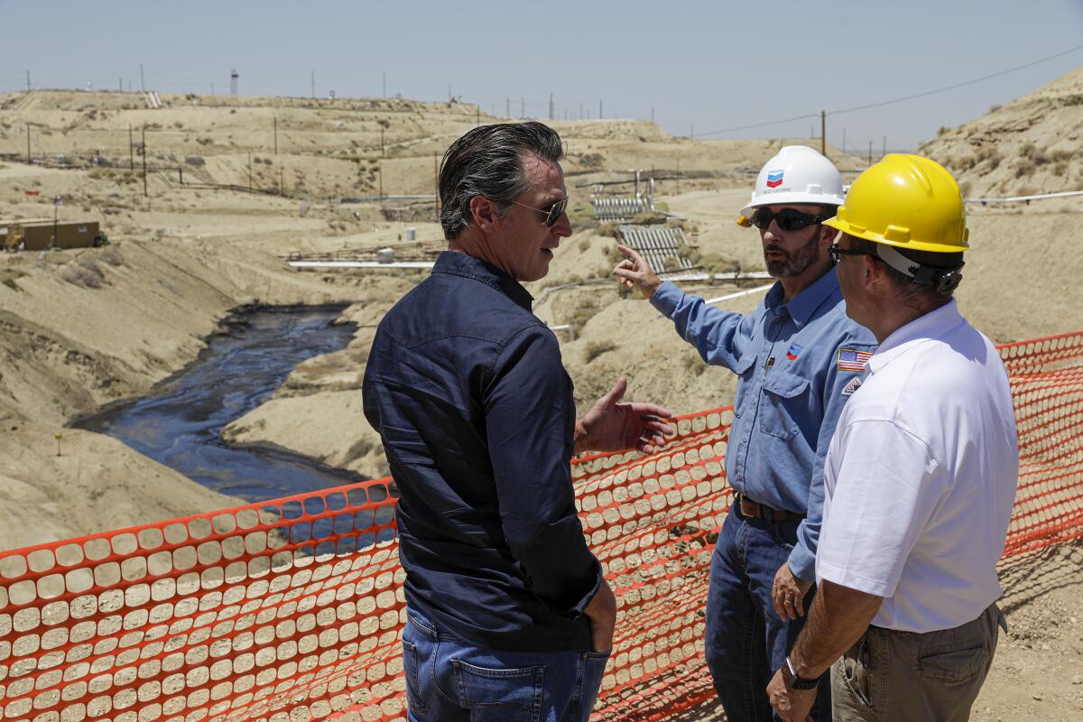 Gov. Gavin Newsom is briefed on a million-gallon spill in McKittrick by Billy Lacobie of Chevron, center, and Jason Marshall of California Department of Conservation Division of Oil, Gas and Geothermal Resources.