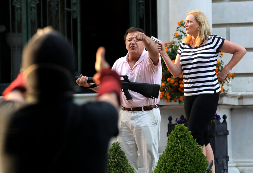 Homeowners Mark and Patricia McCloskey confront protesters marching to the St. Louis mayor's house on Sunday.