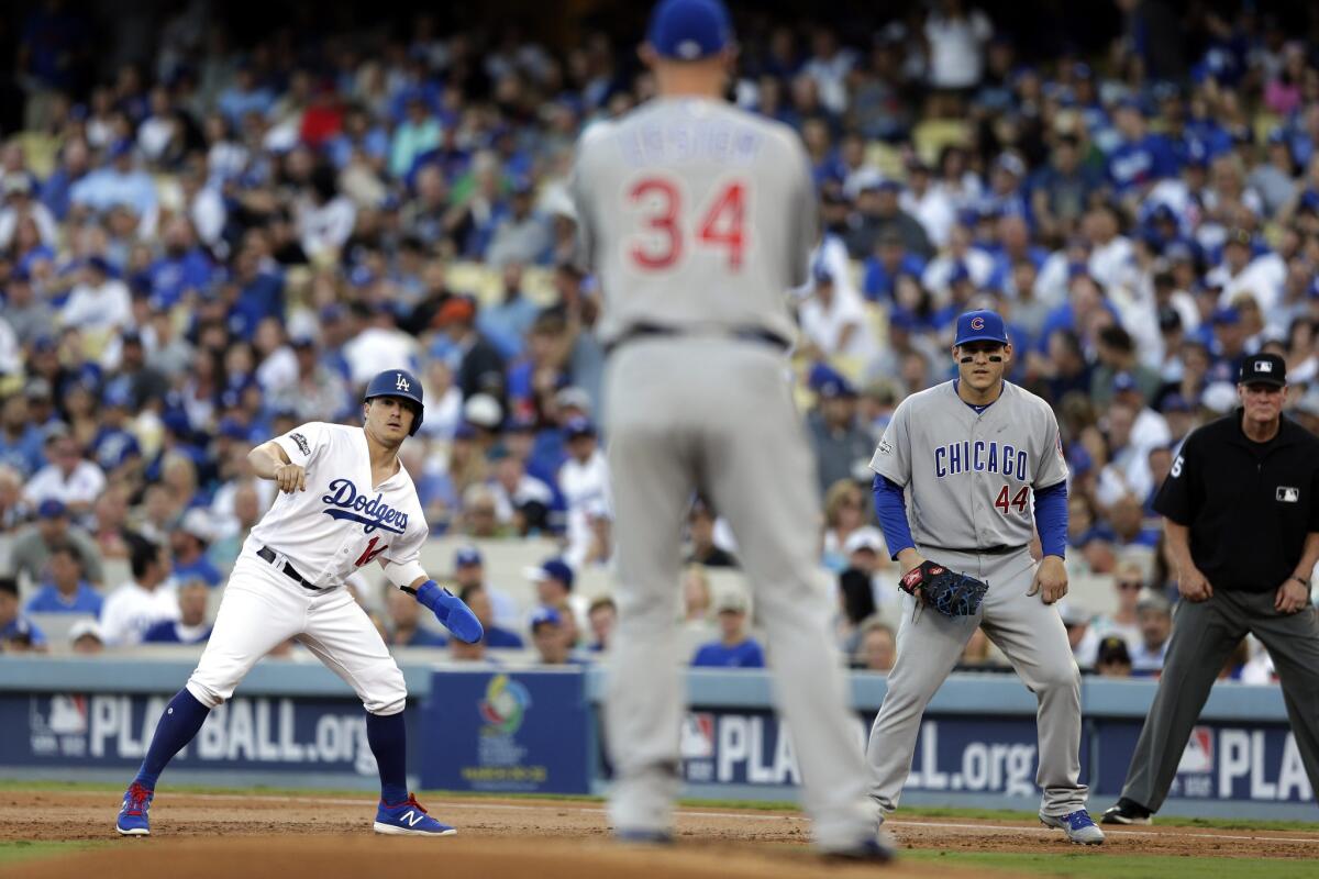 Dodgers baserunner Enrique Hernandez, left, takes his lead off first base as Cubs starting pitcher Jon Lester (34) and first baseman Anthony Rizzo (44) keep an eye on him in the first inning of NLCS Game 5.