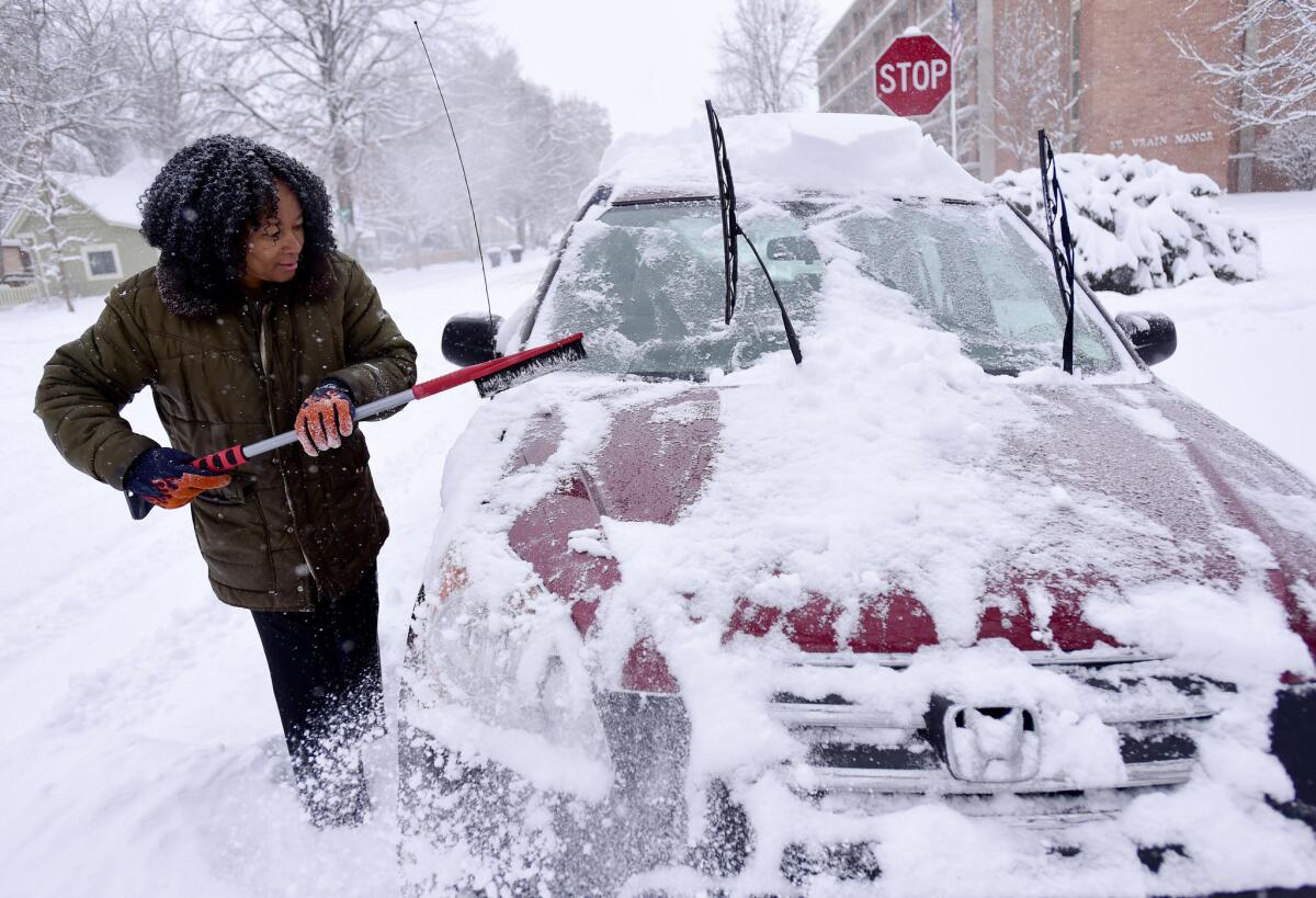 Alexis Miles clears snow from her car Thursday in Longmont, Colo.