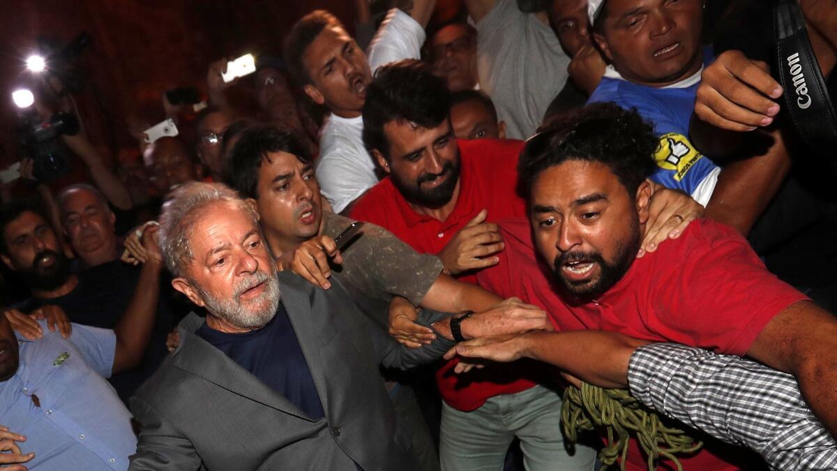 Former Brazilian President Luiz Inacio Lula da Silva, in gray jacket, leaves the Steelworkers Union building in Sao Bernardo do Campo, Brazil, on April 7 2018, to turn himself in to the authorities.