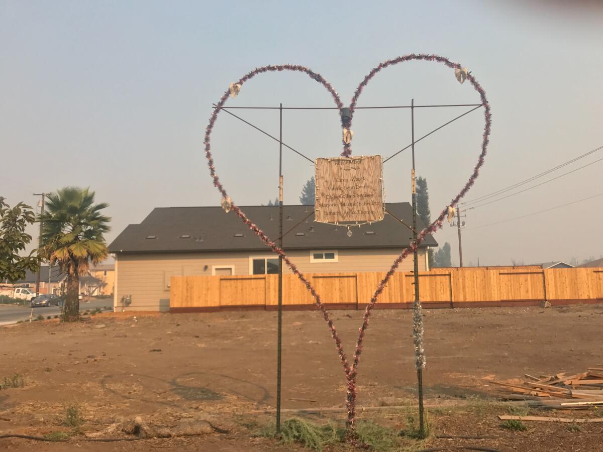 A memorial dedicated to those who died in the 2017 Tubbs fire stands on an empty lot in Coffey Park. A layer of smoke from the Kincade fire surrounds the heart-shaped installation.